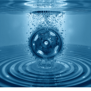 Engrenage métallique immergé dans une eau bleue avec des bulles symbolisant le nettoyage par ultrasons d'objets complexes.